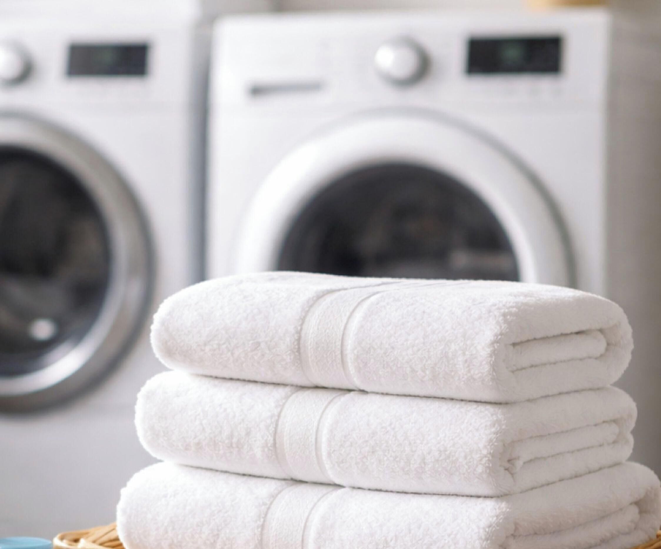A stack of white towels in front of a washing machine.