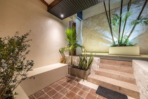 A staircase with a planter box on the landing, a potted plant on the left, and a stone wall in the background. - Casa Provenza 34 6BR With Private Pool (Medellín)