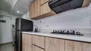 A modern kitchen with wooden cabinets, a stainless steel refrigerator, and a gas stove. - Oslo 1801 in Medell n (Medellín)