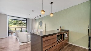 A modern kitchen with a central island, wooden cabinets, and pendant lighting. - Olive Country Living - 205 (Envigado)
