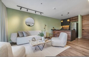 En moderne stue med sofa, lænestol, sofabord og et rundt spejl på væggen.