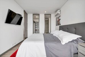 A modern bedroom with a bed, a TV mounted on the wall, a wardrobe, and a staircase leading to an upper level. - Class Suites - 1602 in Medell n (Medellín)