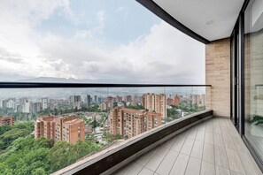 Ein Balkon mit Blick auf die Stadt, ein Fliesenboden und eine Glaswand.