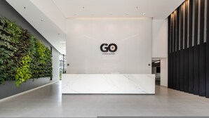 Ein moderner Empfangsbereich mit Marmorplatte, dem Logo von 'GO Living & Suites' und einer vertikalen Begrünung links.