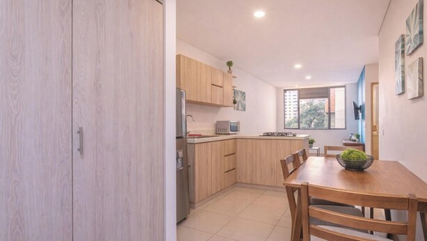 A modern kitchen with wooden cabinets, a dining table, and a view of the city. - Oslo 609 in Medell n (Medellín)