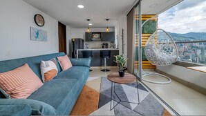 Un salon moderne comprenant un canapé, un coin repas et un balcon agrémenté d’un fauteuil suspendu.