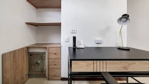 Une chambre équipée d’un bureau, d’un coffre-fort, d’une lampe et d’une prise de courant.
