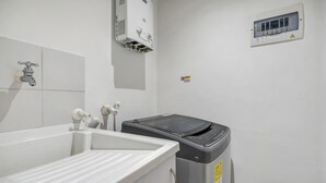 Une salle de bain équipée d’un lavabo, de toilettes, d’une poubelle et d’un radiateur fixé au mur.
