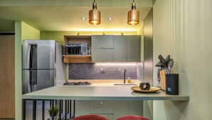 Une cuisine moderne avec un réfrigérateur en acier inoxydable, un comptoir en marbre et des tabourets de bar rouges.