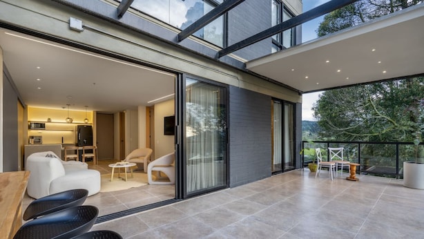 A modern interior with a kitchen, seating area, and a balcony with a view. - Olive Country Living - 117 (Envigado)