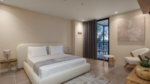 A modern bedroom with a large bed, a small round table, a chair, and a view through a glass door. - Olive Country Living - 117 (Envigado)