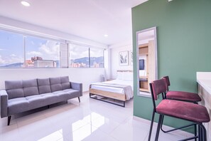 Una habitación moderna con una cama, un sofá gris y una silla roja.