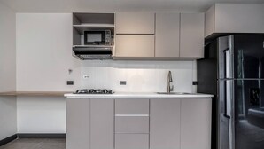 Eine moderne Küche mit einem Edelstahl-Kühlschrank, einer Mikrowelle und einem Gasherd.