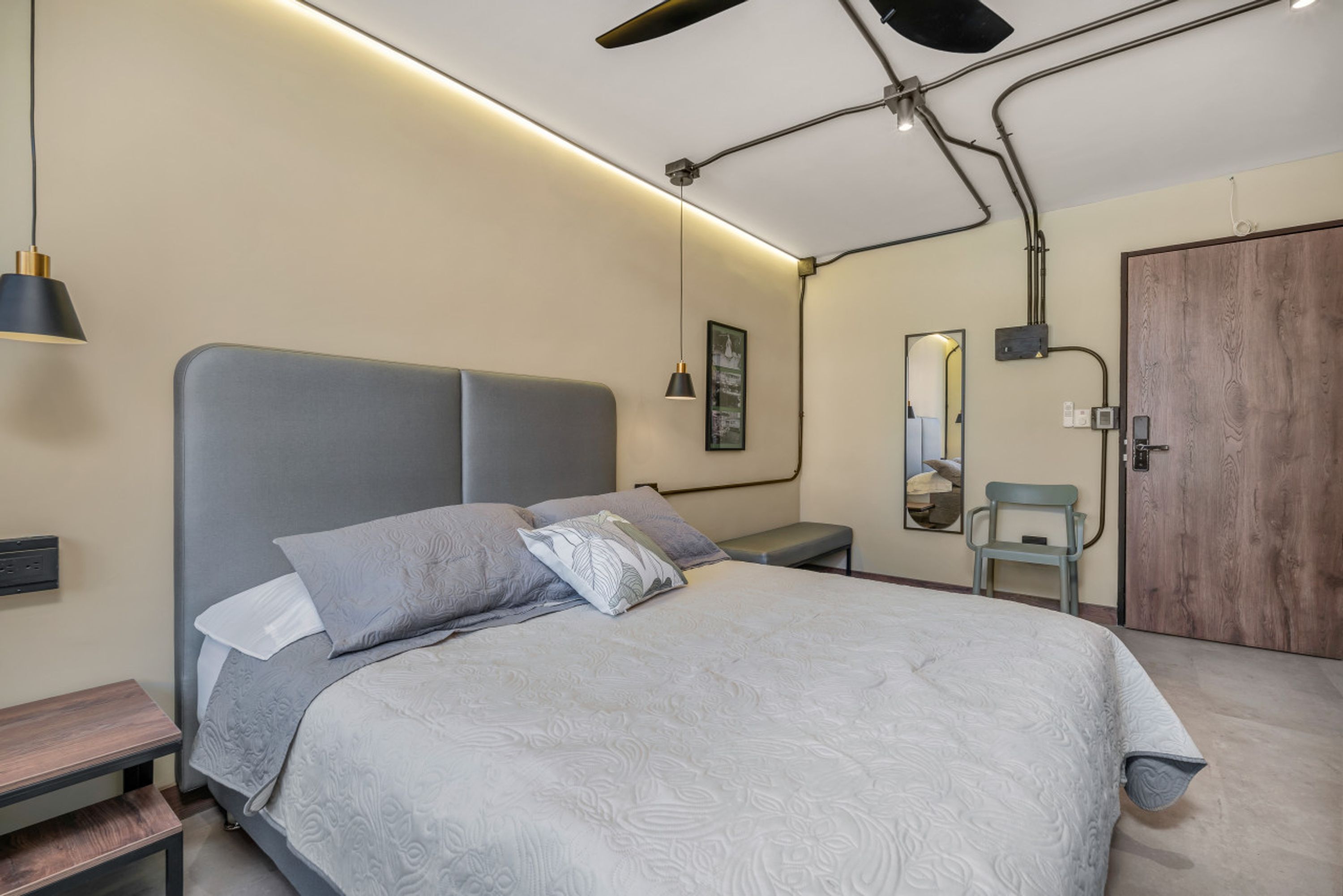 Een moderne slaapkamer met een bed, nachtkastjes, een bankje, een spiegel en een deur.