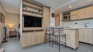 Una cocina moderna con armarios de madera, televisor integrado y una zona de bar con taburetes.