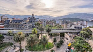 A cityscape with a prominent building, palm trees, and a bridge. - Nutibara Express - 831 (Medellín)
