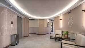 A modern interior with a curved ceiling, a seating area with a table and chairs, and directional signs indicating levels. - Nutibara Express - 831 (Medellín)