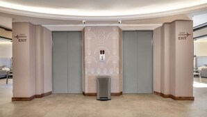 A hotel lobby with two doors marked 'EXIT' and an elevator with a decorative wall. - Nutibara Express - 831 (Medellín)
