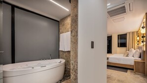 A modern bathroom with a freestanding bathtub, a large mirror, and a vanity with a sink. - LIN Hotel Suite Deluxe (Medellín)