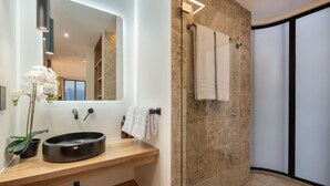 Une salle de bain moderne avec un meuble-lavabo en bois, un lavabo rond, un miroir, un porte-serviettes et une cabine de douche en verre.