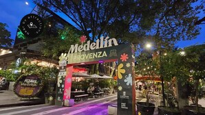 Une vue nocturne de l’entrée d’un restaurant appelé « Medellín Provence », avec une terrasse et des éclairages décoratifs.