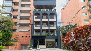 A multi-story building with a brick facade, balconies with plants, and a central entrance with a canopy. - Opera 303 in Medell n (Medellín)