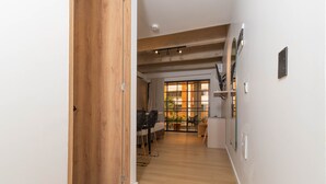 A hallway with wooden flooring, a dining area with chairs and a table, and a view through a glass door to an outdoor area. - Opera 303 in Medell n (Medellín)
