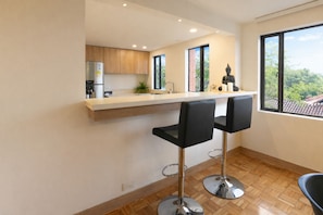 Eine moderne Küche mit Bar, Holzschränken, einem Kühlschrank und Blick durch große Fenster.