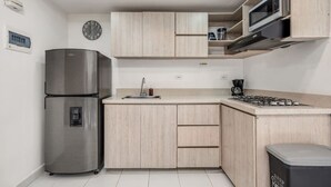 A modern kitchen with a stainless steel refrigerator, wooden cabinets, a microwave, and a gas stove. - Oslo 704 in Medell n (Medellín)