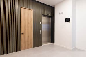 Ein Flur mit einer Holztür, einer Wand mit vertikalen Streifen und einem Aufzug.
