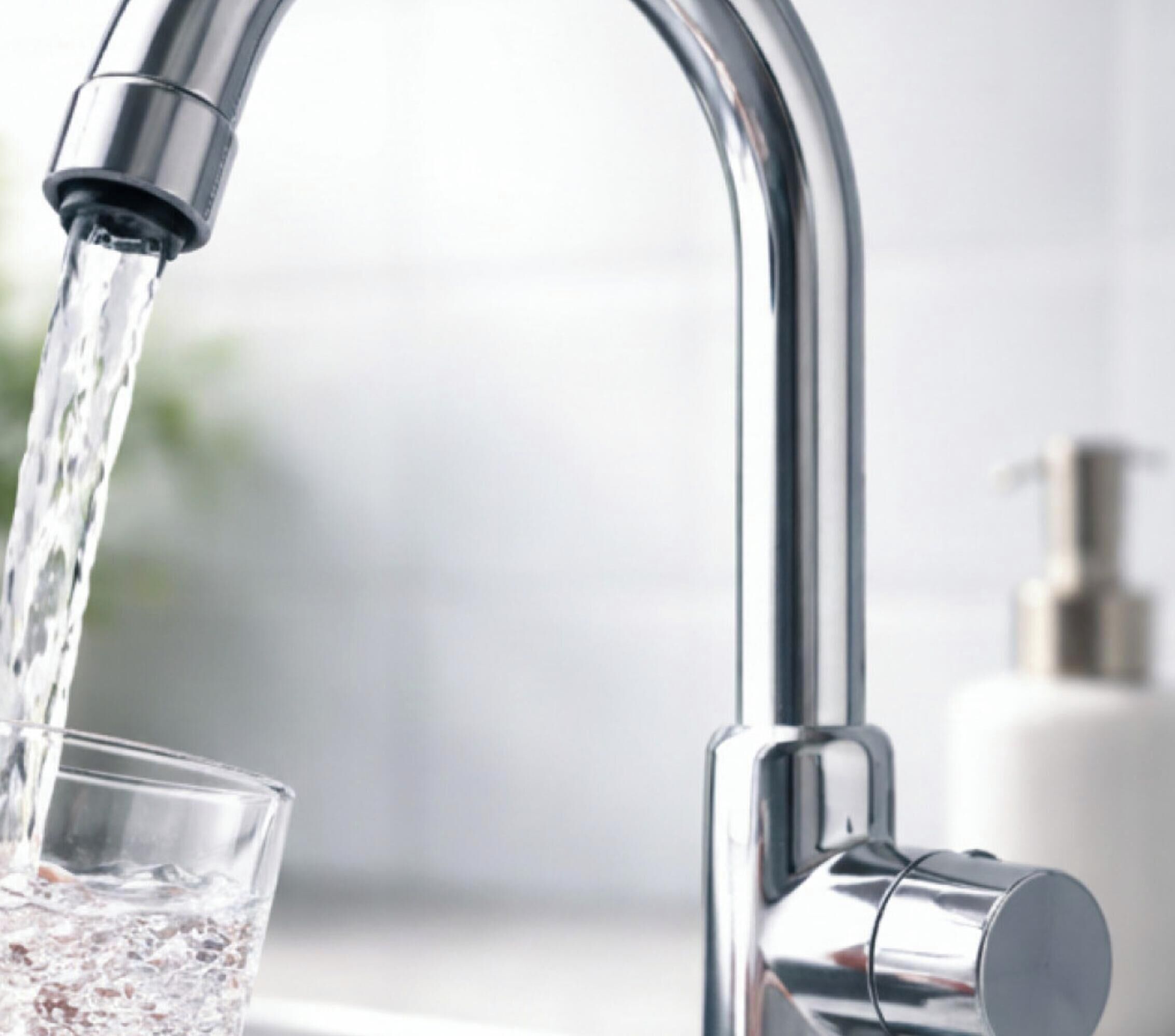 A modern faucet with water flowing into a glass.