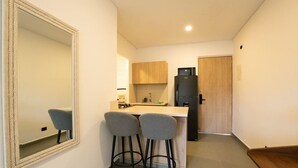 Una cocina compacta con una zona de asientos con taburete, un refrigerador y una puerta de madera.