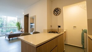 Cocina moderna con encimera de madera, un reloj en la pared y vistas a un balcón con cama y planta.