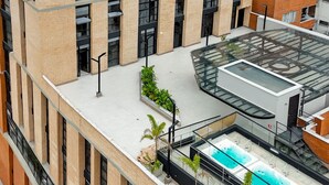 A high-rise building with a rooftop pool area, multiple windows, and a glass-enclosed section. - Metropolitan Living - 1615 (Medellín)