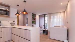 A modern apartment with a kitchen, dining area, and a living room with a sofa and a small table. - Jatisa 303 in Medell n (Medellín)