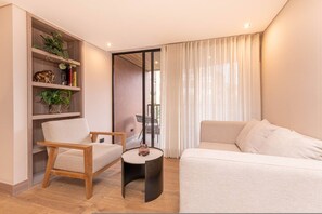 A modern living room with a sofa, a chair, a small table, and a bookshelf with plants and decorative items. - Jatisa 303 in Medell n (Medellín)