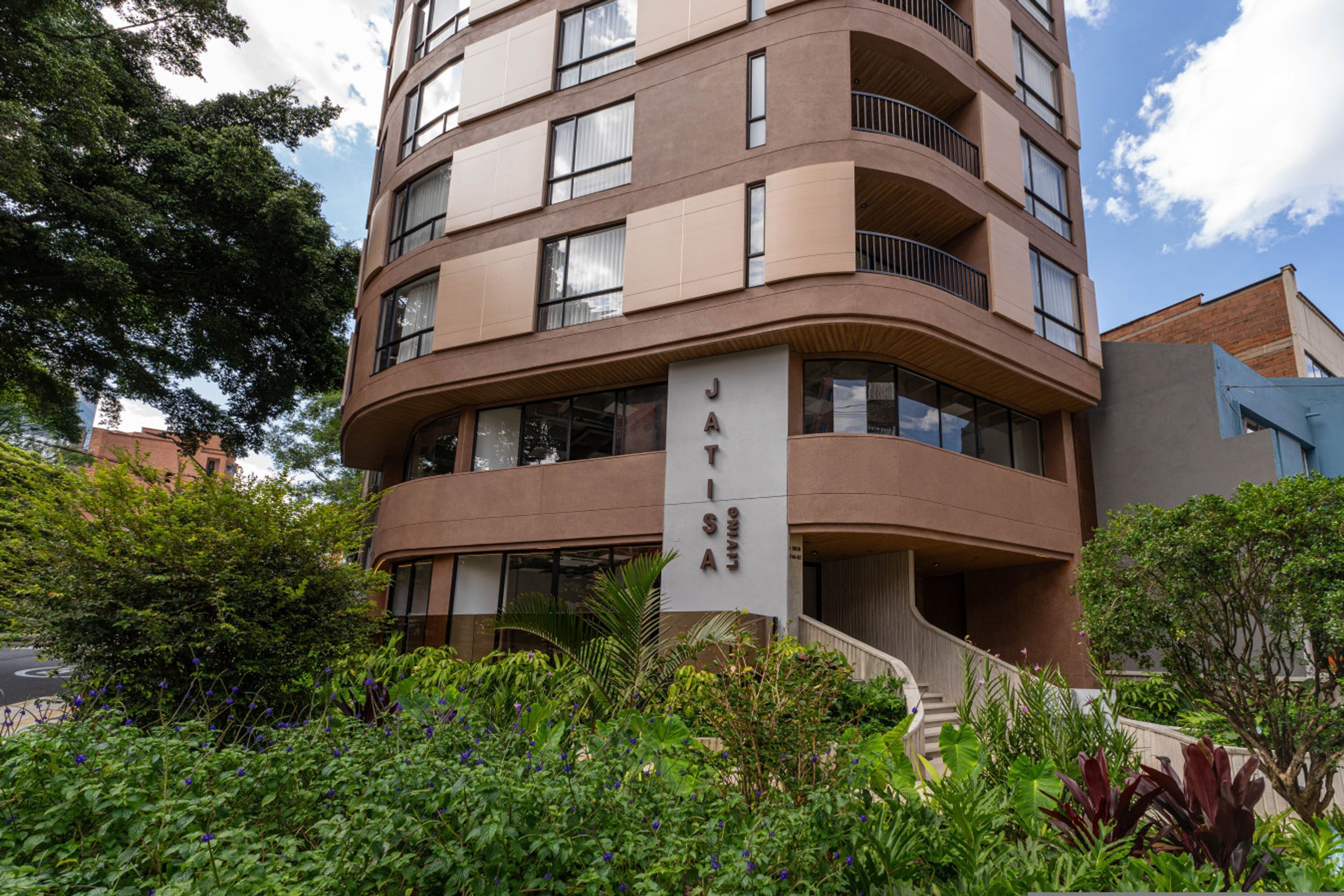 A multi-story building with a curved facade, balconies, and a sign reading 'JATISIA.'