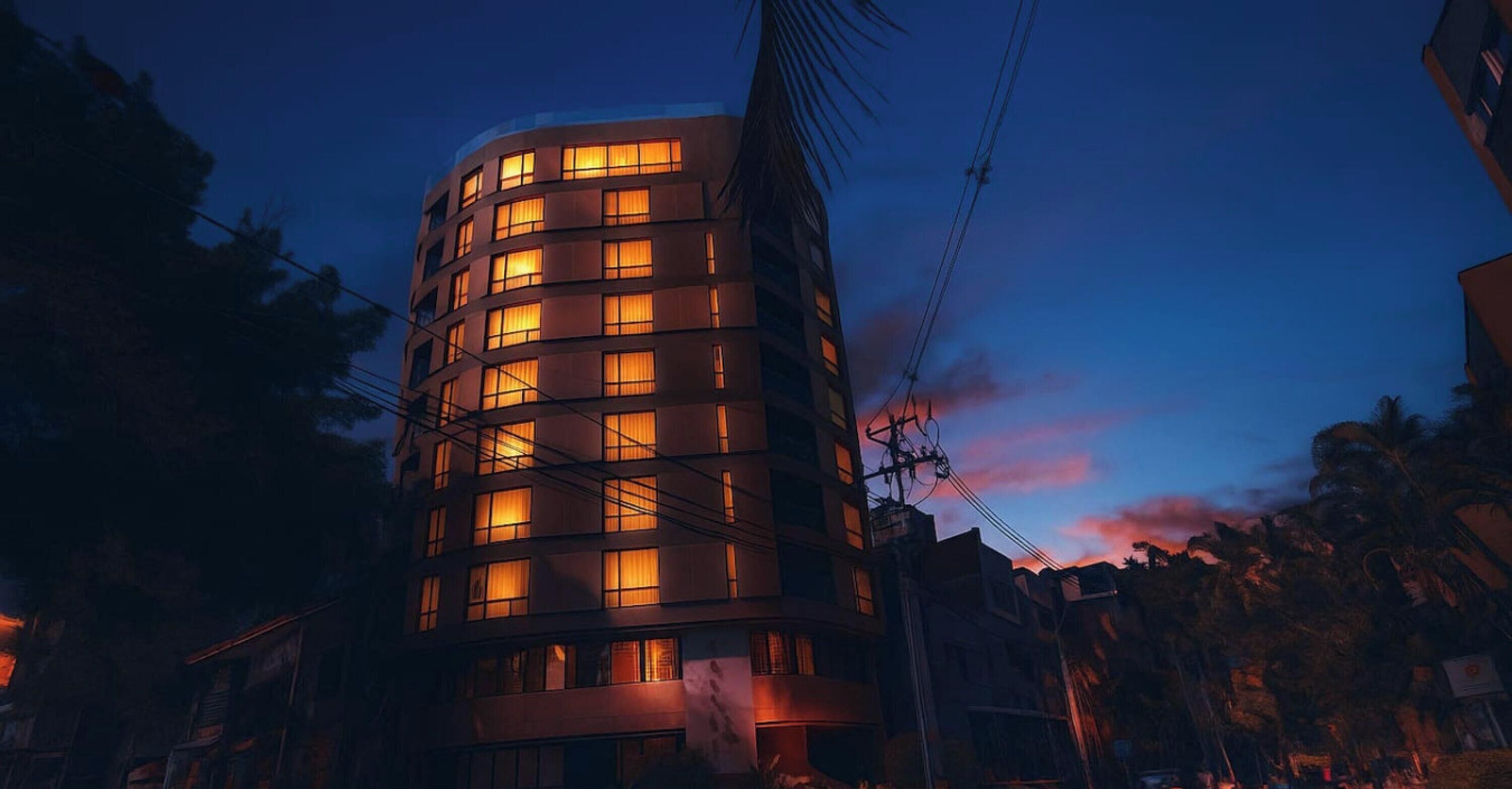 A multi-story building with illuminated windows at dusk.