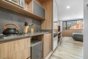 A modern kitchen with wooden cabinets, a kettle, and utensils on the counter. - Go Living Suites - 1013 (Medellín)