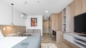 Ein modernes Hotelzimmer mit Bett, Sofa, Fernseher und einem Bild an der Wand.