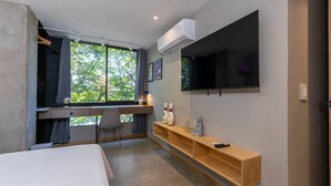 A bedroom with a bed, a desk, a chair, a TV mounted on the wall, and a window with a view of trees. - Ayamonte - 105b in Medell n (Medellín)