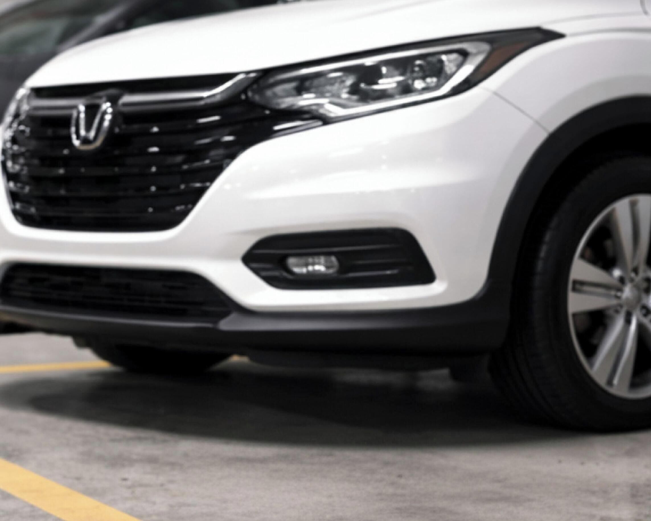 A white vehicle with a visible logo on the front grille.