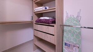 Une armoire en bois avec plusieurs étagères, une couverture violette et un objet à motifs verts sur la droite.