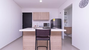 Une cuisine moderne avec un îlot central, des meubles en bois, un réfrigérateur et une horloge au mur.