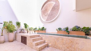 A stone staircase leading to a pool area with potted plants and a circular wall feature. - Casa Museo - Standar (Medellín)