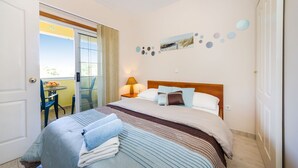 Een hotelkamer met een bed, een nachtkastje met een lamp, uitzicht door een glazen deur en een muur met ronde decoraties.