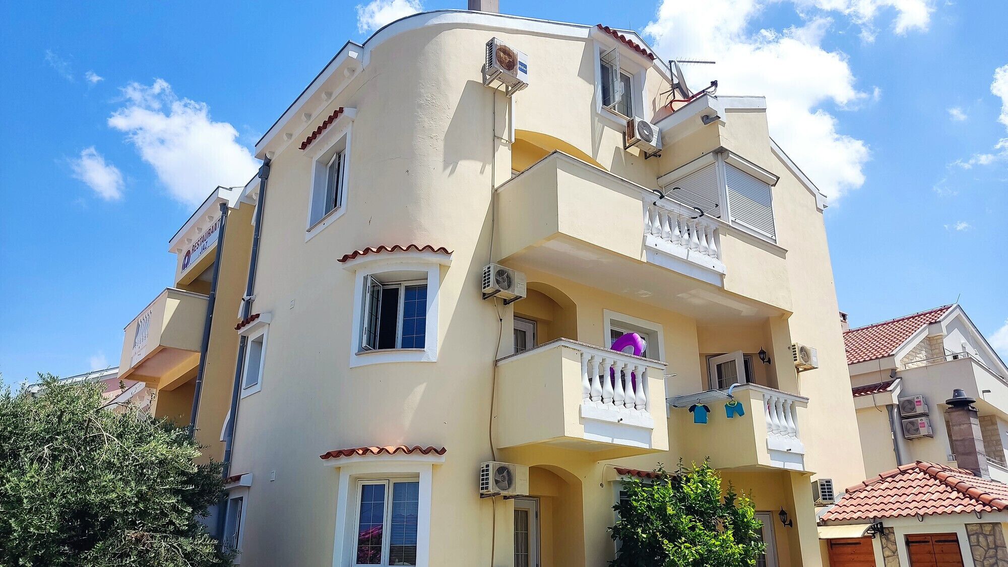 A multi-story building with balconies, air conditioning units, and a restaurant sign.