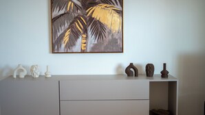 Una stanza moderna con un armadietto bianco, vasi decorativi e un quadro incorniciato con palme.