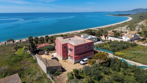 Una proprietà costiera con un edificio rosso, una spiaggia e una vista chiara sul mare.