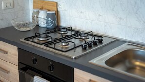 Una cucina con piano cottura a gas, lavello in acciaio inossidabile e zoccolo a mosaico di marmo.